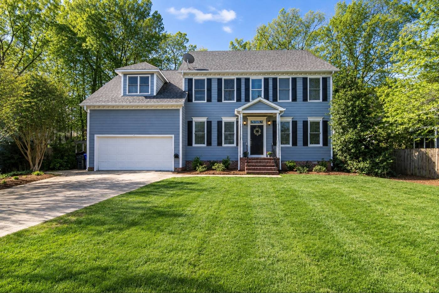 Blue two-story home with a freshly striped front lawn